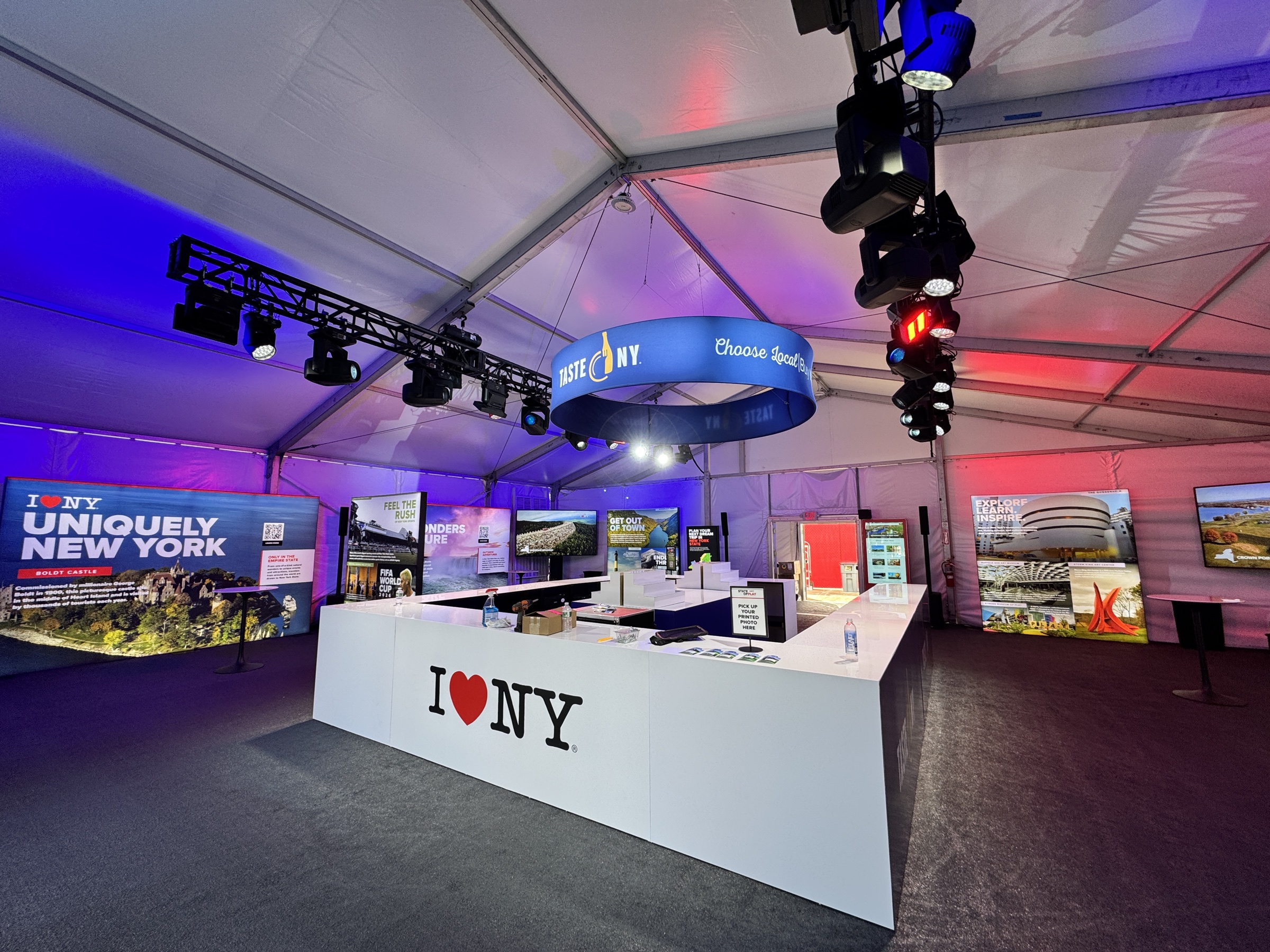 The completed I LOVE NY activation at the 2025 Ryder Cup illuminated with blue and magenta event lighting
